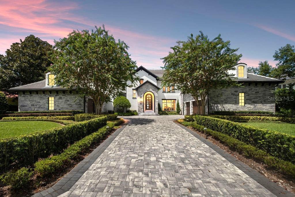 Laurel Valley grand luxurious estate at dusk with modern European and contemporary farmhouse architecture, stone wings, and patterned paver driveway